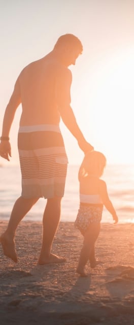 Father and son walking along the beach at sun set