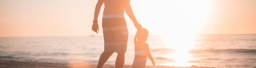 Father and son walking along the beach at sun set