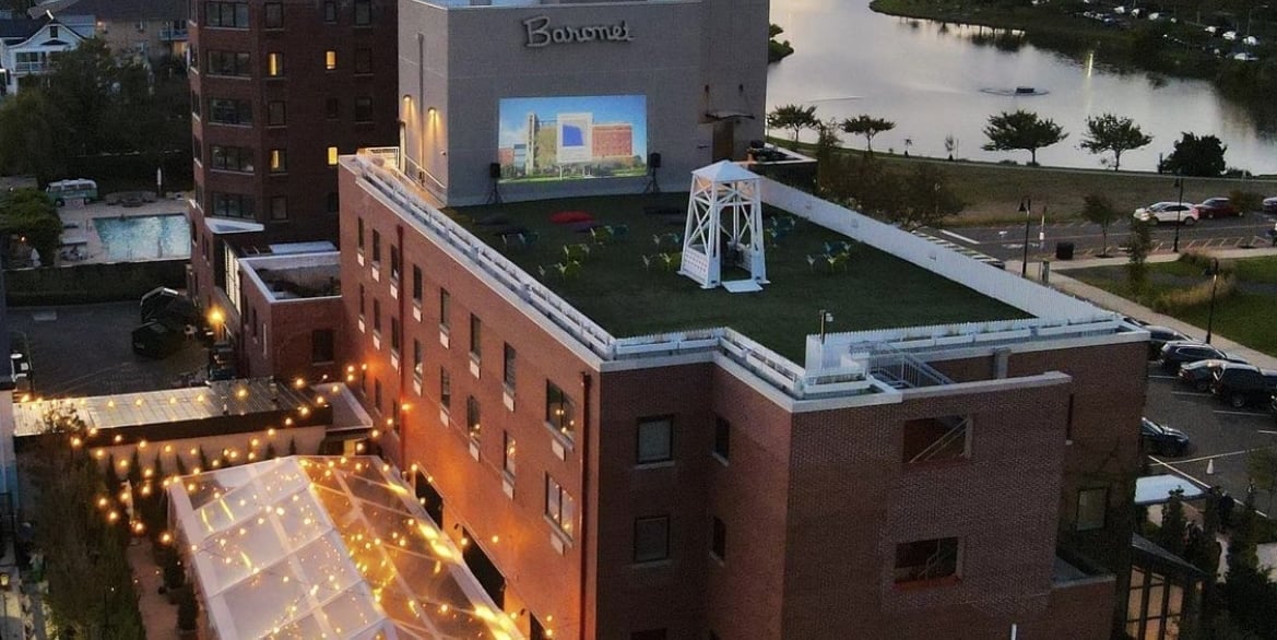 The Asbury Hotel, Asbury Park: Vibrant Baronet rooftop cinema, sparkling pool, and welcoming outdoor social areas at dusk.